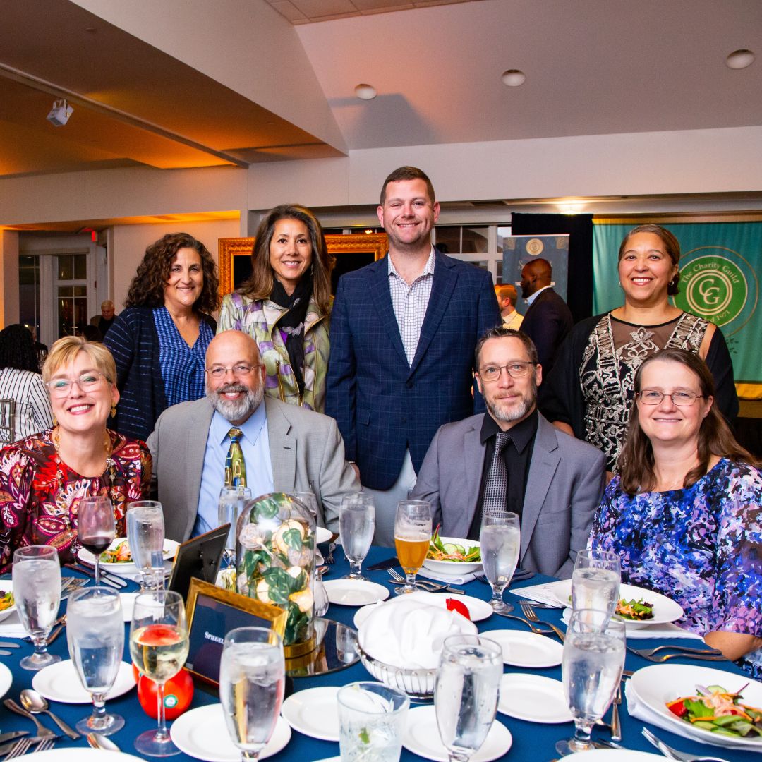 Group of people poses at a table, all smiling